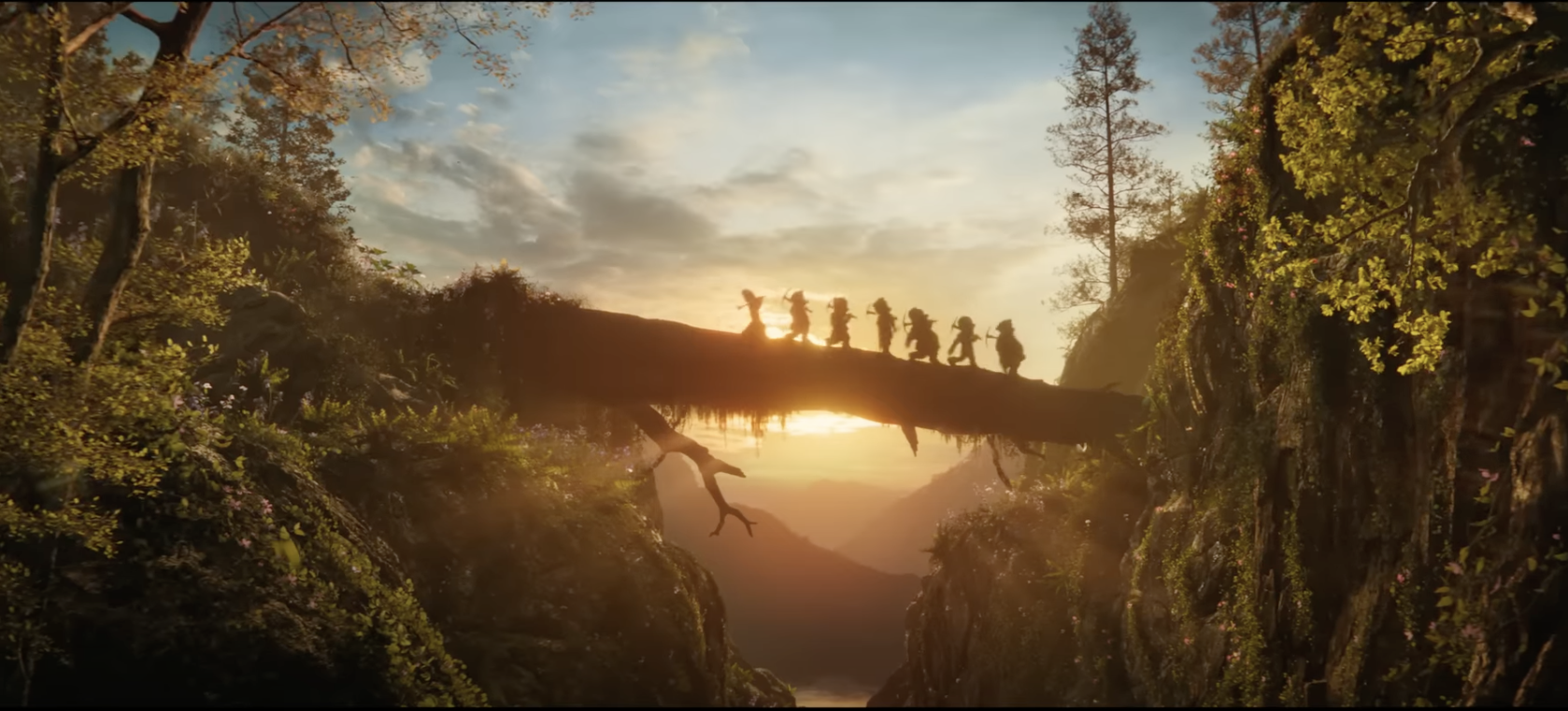 film still from Snow White showing the seven dwarves walking across a tree trunk