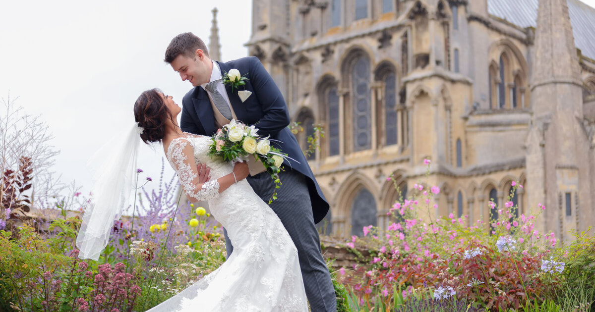 wedding photo of couple with Ely Cathedral and gardens in the backdrop
