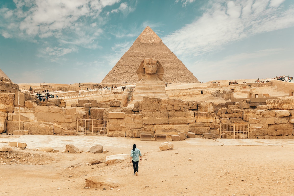 Tourist walking toward the Great Sphinx and Pyramid of Khafre at Giza, Egypt – a world-famous filming and scouting location